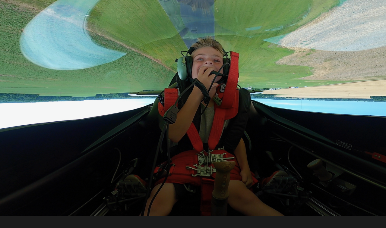 Child experiencing inverted aerobatic flight in the XA-42 cockpit, laughing